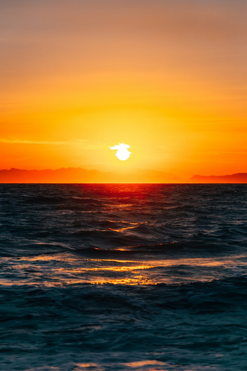 太陽は波とともに海に沈んでいます