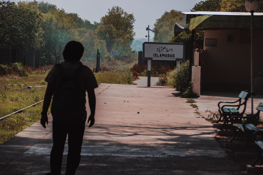 a man walking down a sidewalk next to a train station