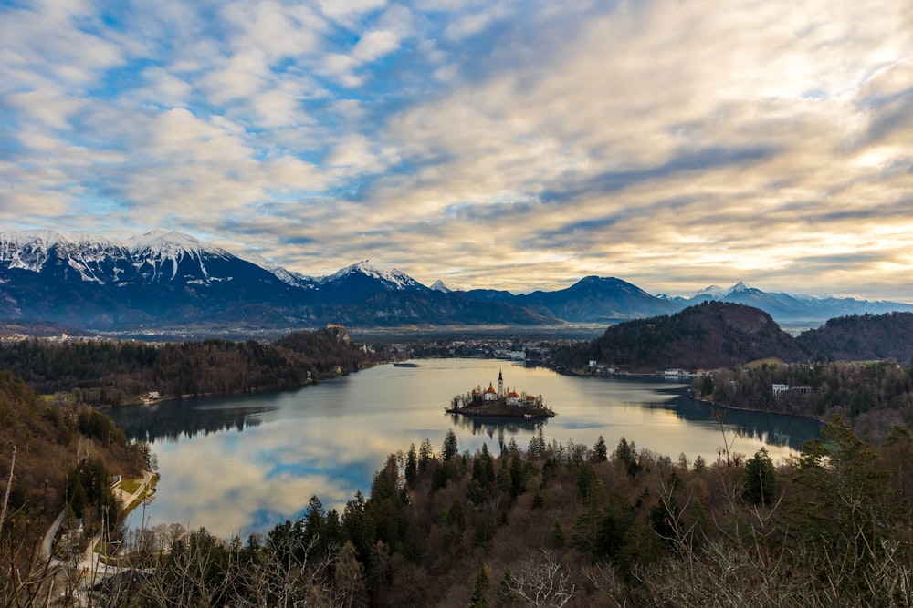 a lake surrounded by mountains under a cloudy sky