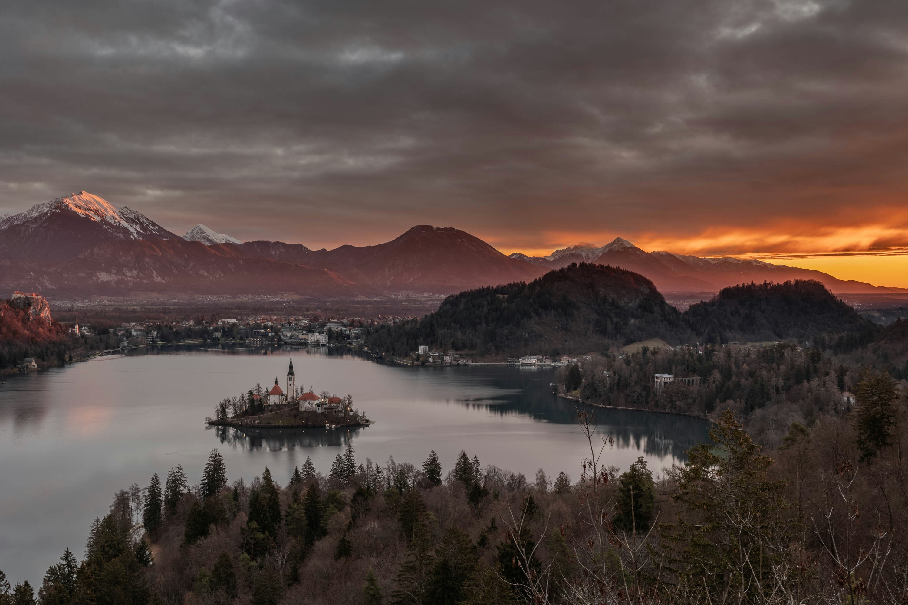 a lake surrounded by mountains under a cloudy sky, Sunrise on the mountains surrounding Lake Bled - Beautiful landscapes of Slovenia