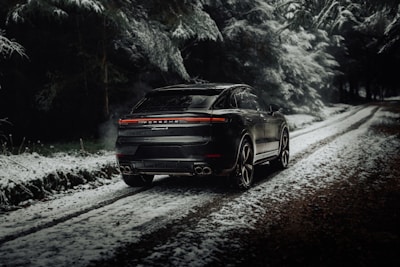 Spacious black SUV driving through a forest road.