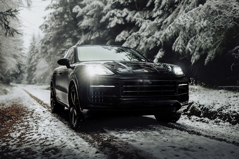 Ein schwarzer Sportwagen fährt eine verschneite Straße entlang