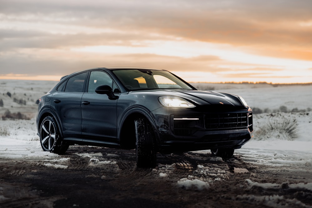 a black porsche cayen is parked in the snow