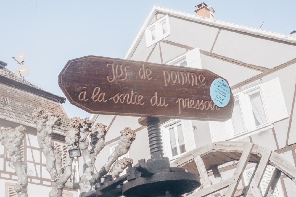 un panneau en bois avec une inscription dessus devant un bâtiment