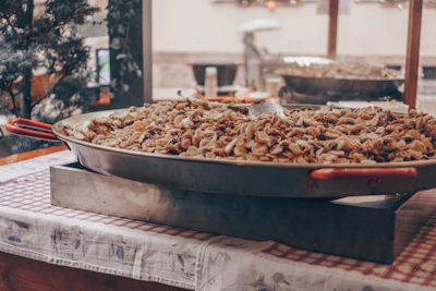 Artisan carefully applying masala coating to nuts in a traditional panning machine.