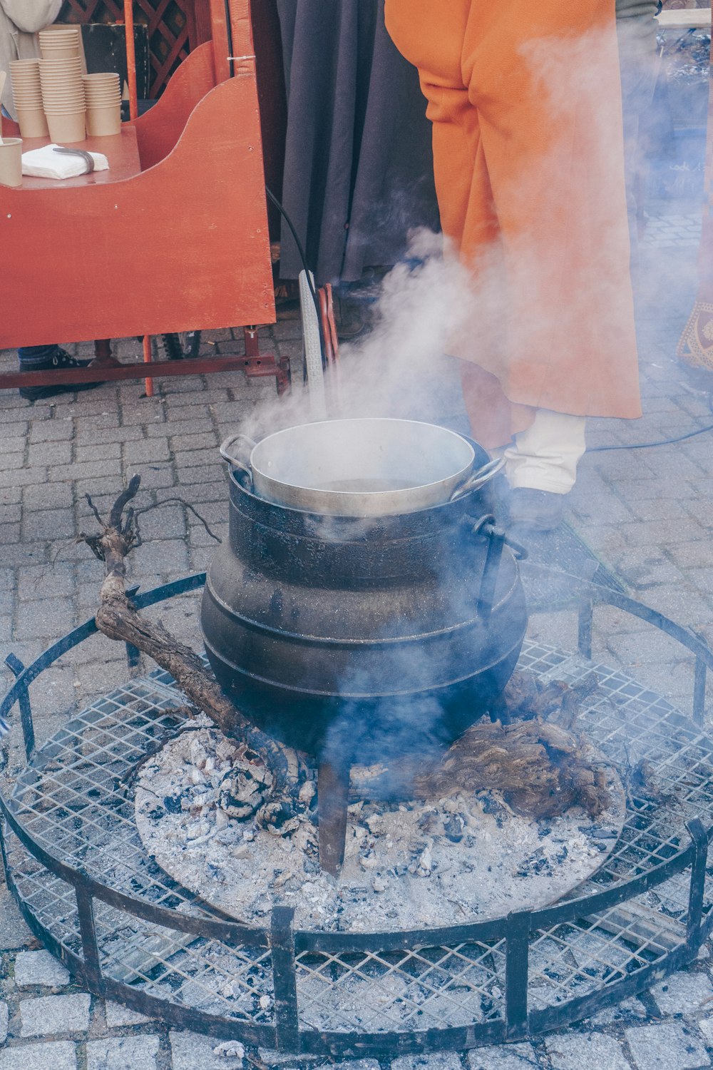 une personne debout au-dessus d’une casserole au-dessus d’un gril