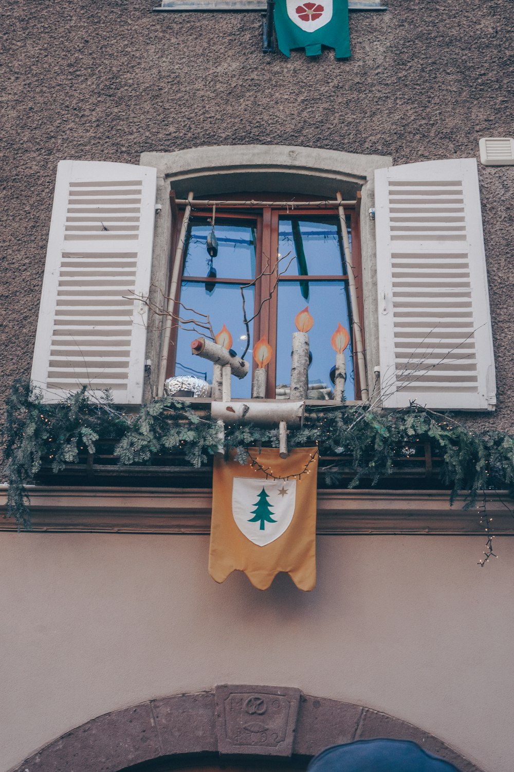 Uma janela com uma decoração de Natal pendurada ao seu lado