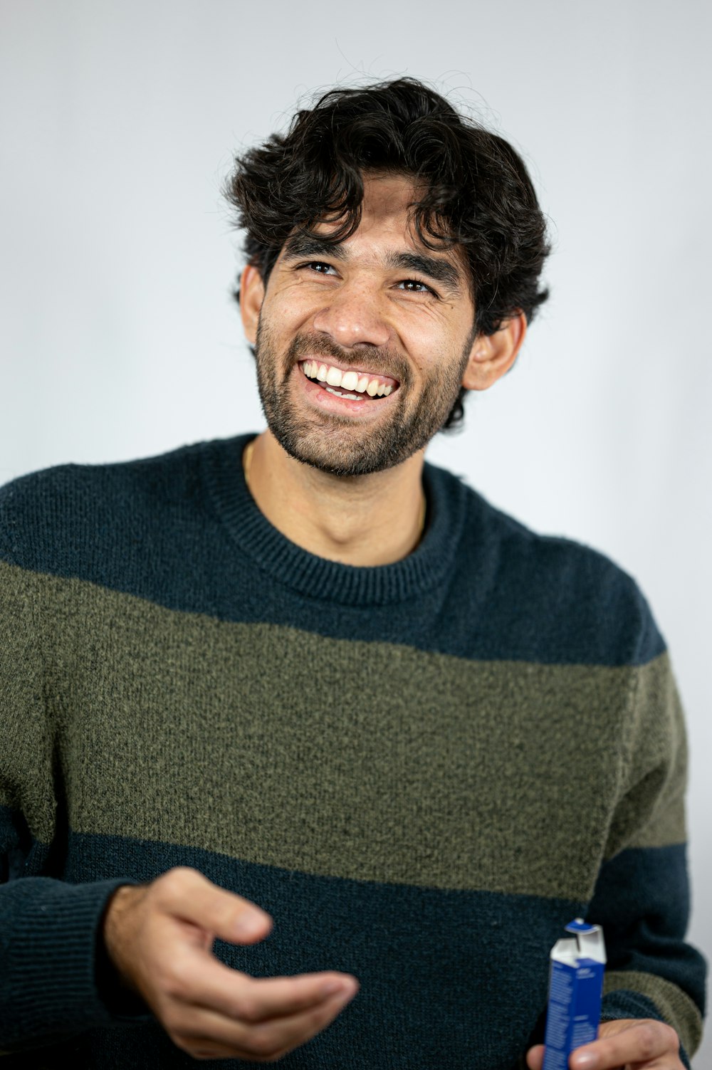 a man with curly hair smiling and holding a toothbrush