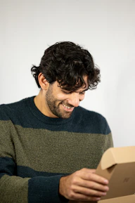 Smiling customer unboxing a package from nexora, showing excitement and satisfaction.