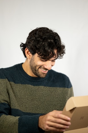 A happy customer unboxing a package from bachter, smiling with excitement.