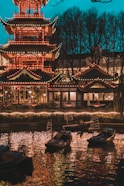 a chinese pagoda lit up at night with boats in the water