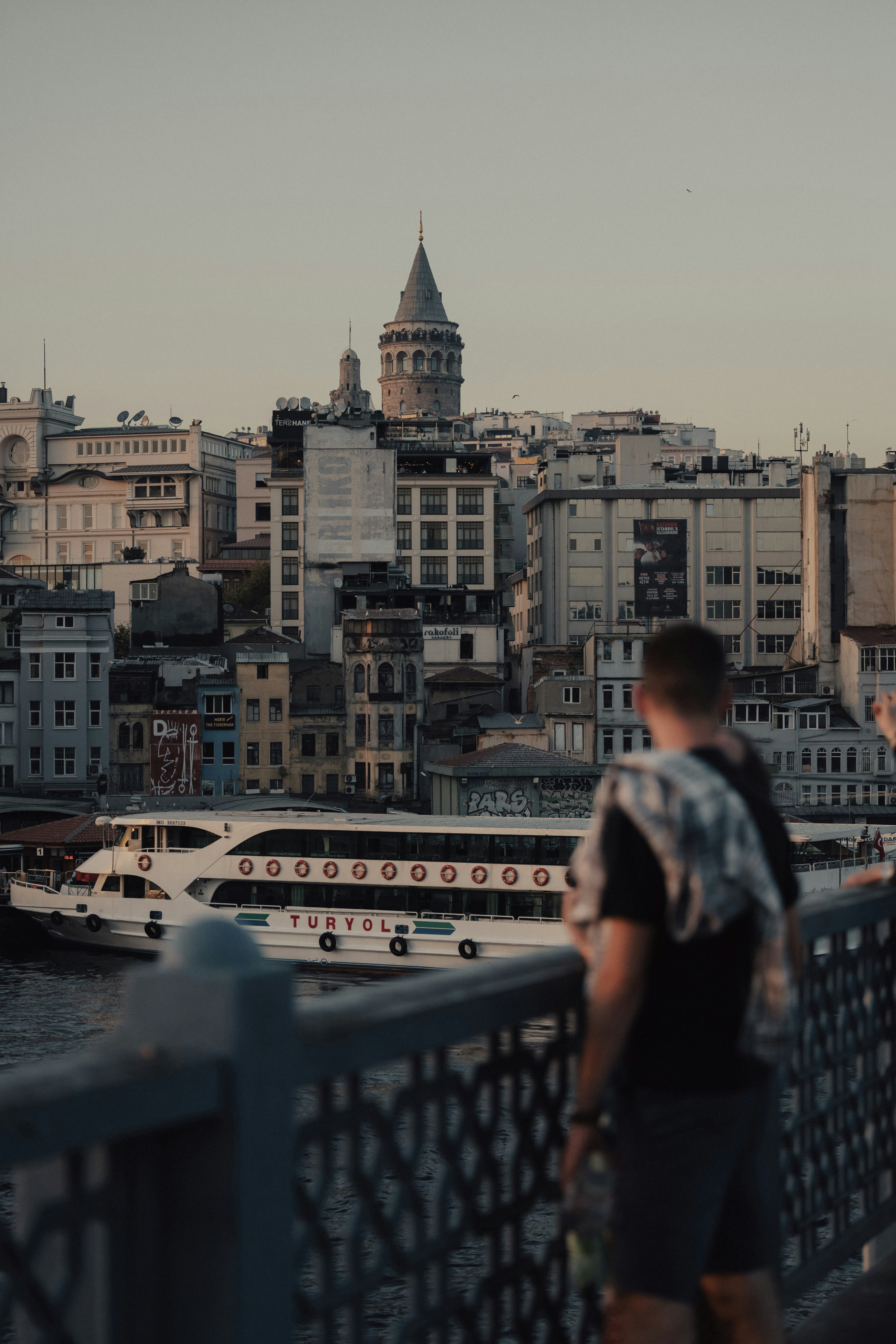 a man standing on a bridge looking at a boat