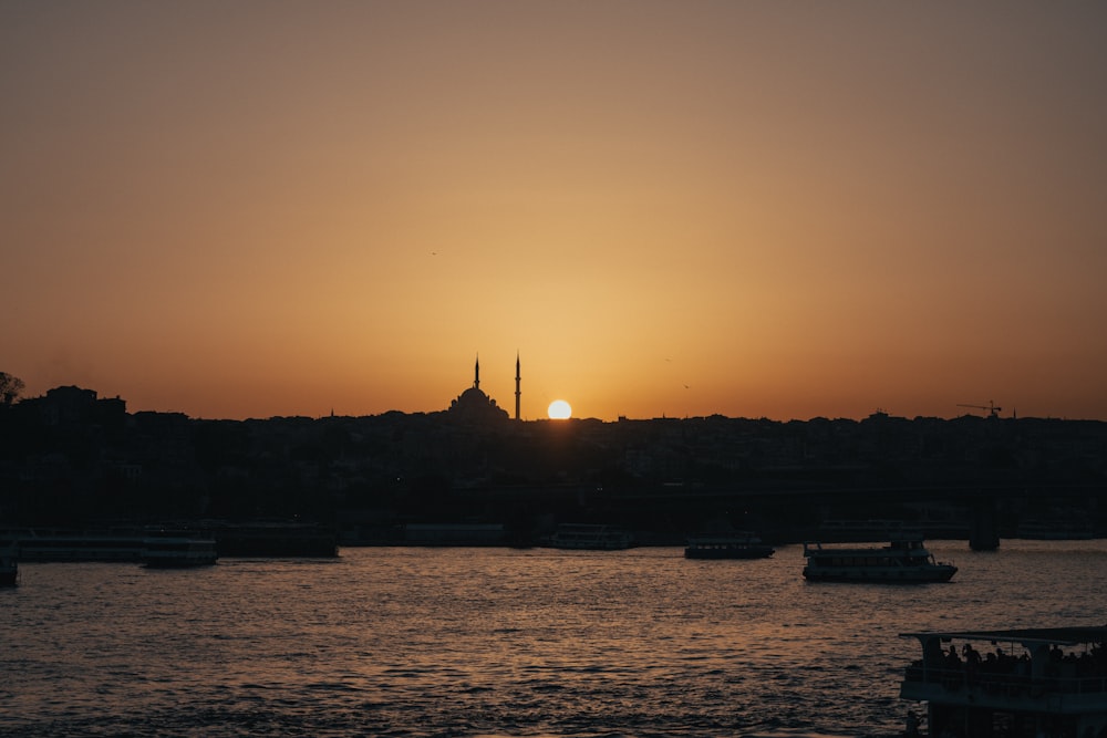 um pôr do sol sobre um corpo de água com barcos na água