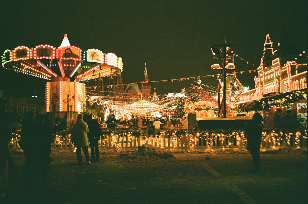 a carnival with people walking around it at night