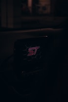 A car dashboard with a screen displaying the logo 'ST' surrounded by a hexagonal pattern, illuminated in a dark environment.