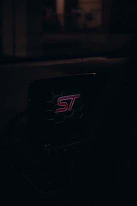 A car dashboard with a screen displaying the logo 'ST' surrounded by a hexagonal pattern, illuminated in a dark environment.