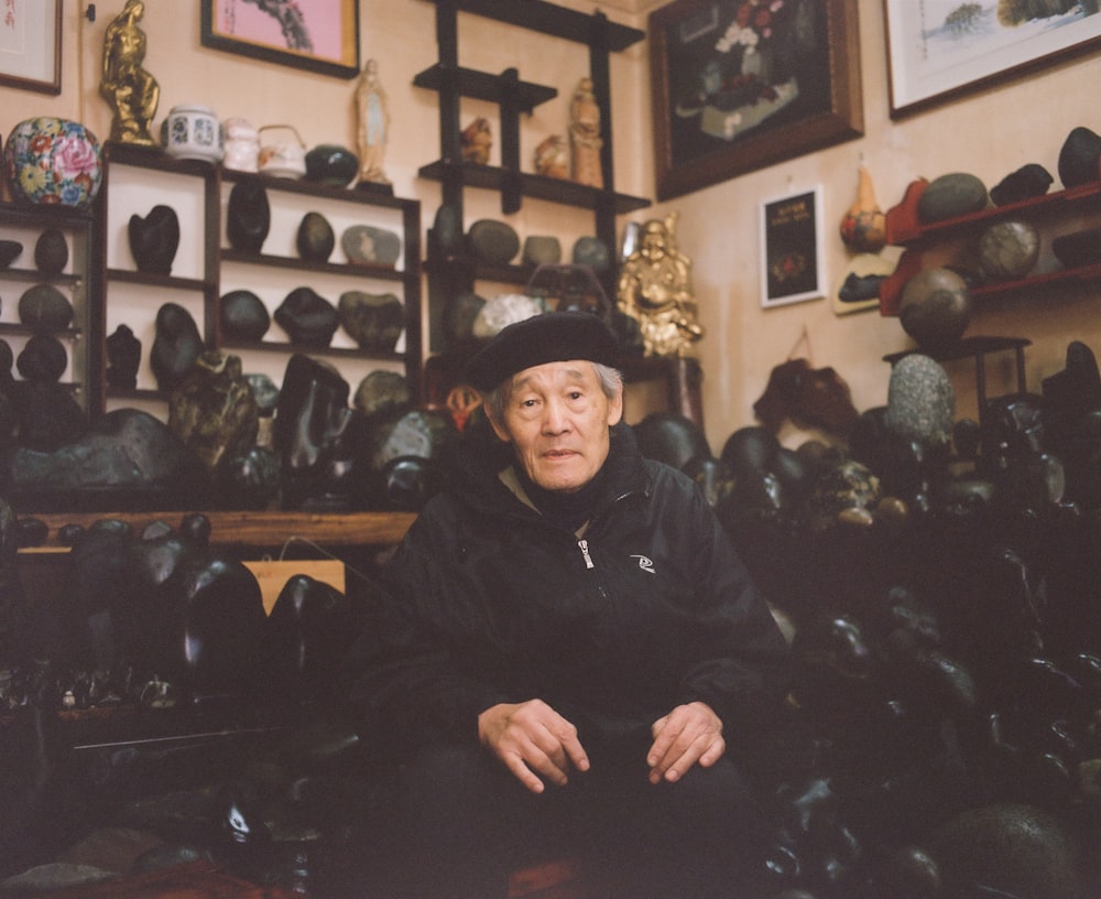 a man sitting in a room filled with lots of hats