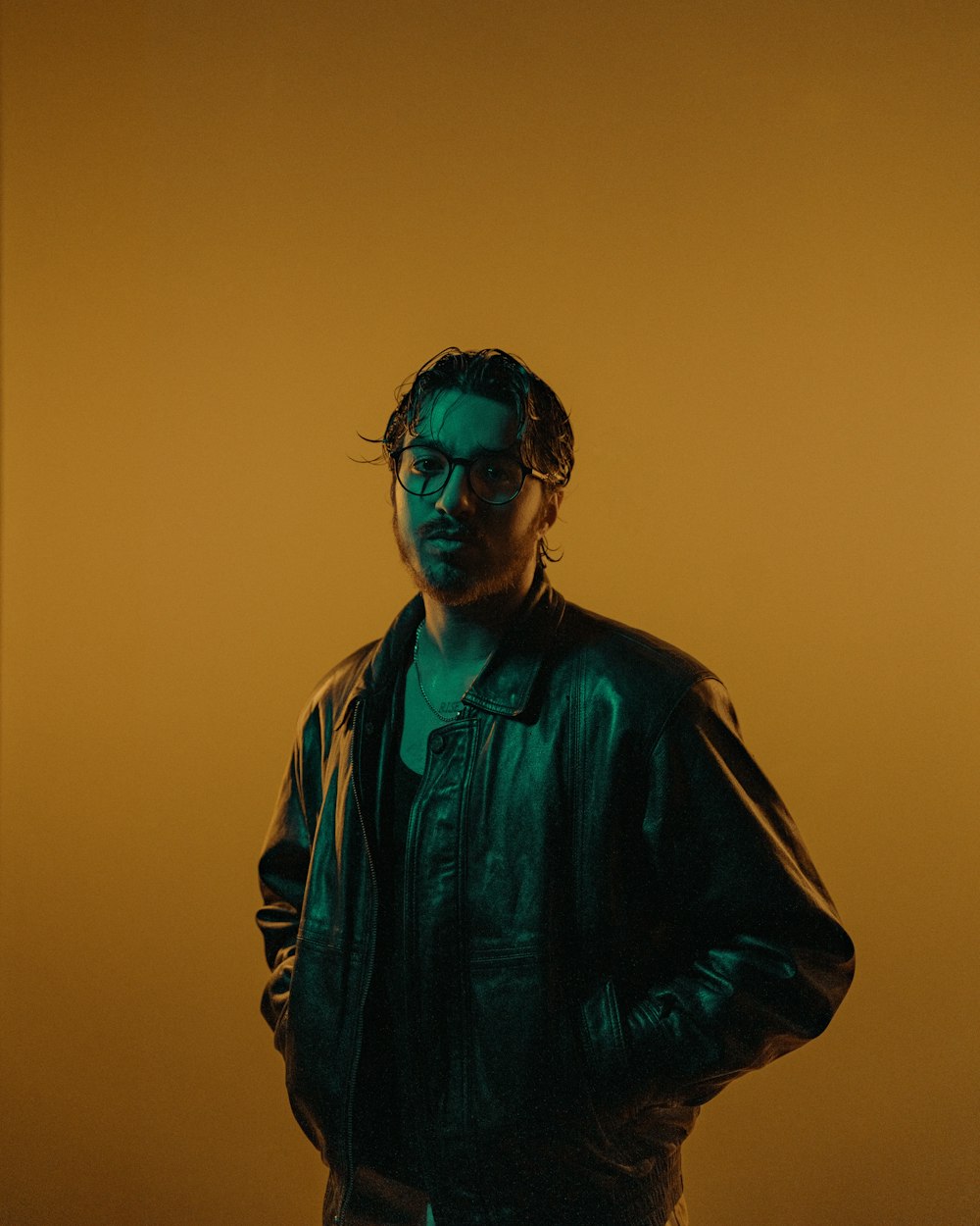a man in a leather jacket standing in front of a yellow background