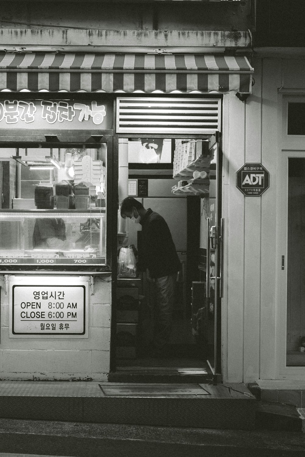 a black and white photo of a man standing outside of a store