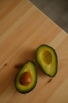 A fresh green avocado sliced in half on a white kitchen counter, symbolizing healthy keto fats.