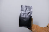 Hands holding the sealed retort pouch of cooked rice against a blue and yellow background