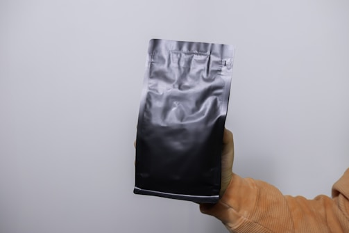 A close-up of a hand holding an open Vybe pouch container, showing the smooth texture of the pouches inside.