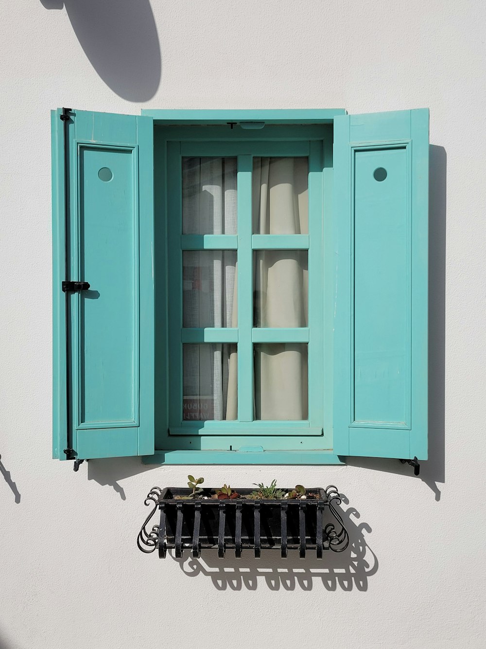 a window with blue shutters on a white wall