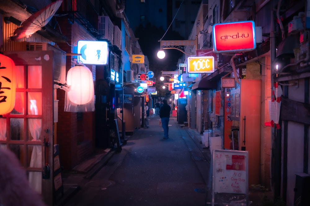a person walking down a narrow alley way at night