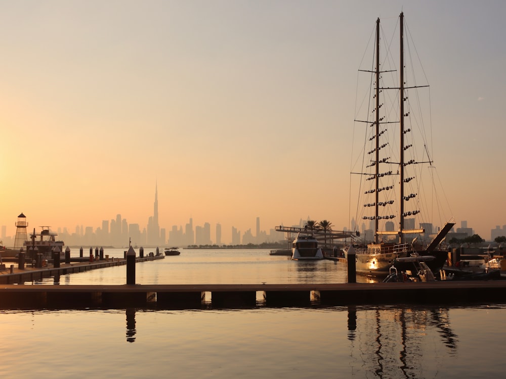 a sailboat docked in a harbor with a city in the background