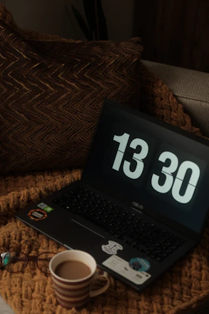 A cozy home setup with a laptop showing a live stream and a cup of coffee nearby.