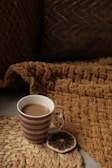 A cozy ceramic mug with a soft matte finish resting on a wooden table beside a warm knitted blanket.