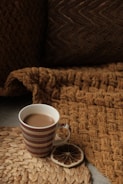 A close-up of a steaming mug filled with coffee on a cozy blanket.