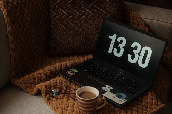 A cozy workspace with a laptop, a cup of tea, and a soft knitted blanket representing comfort and care.