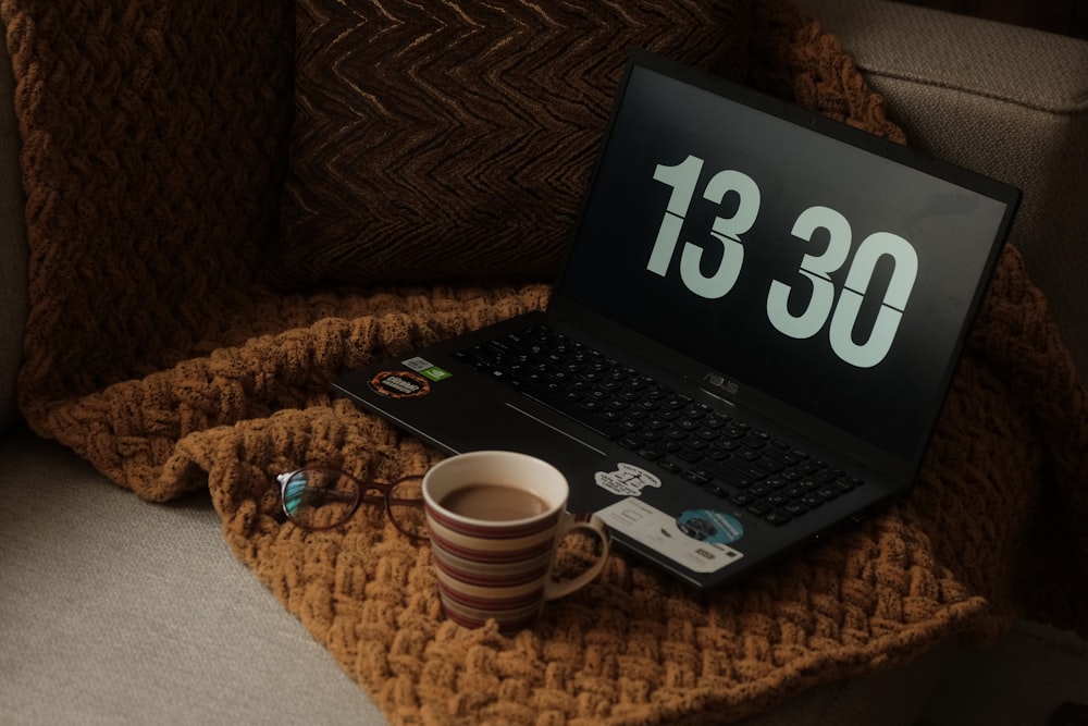 a laptop computer sitting on top of a couch next to a cup of coffee