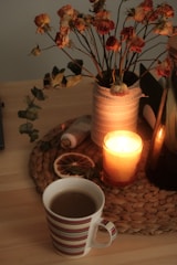 a cup of coffee next to a vase with flowers