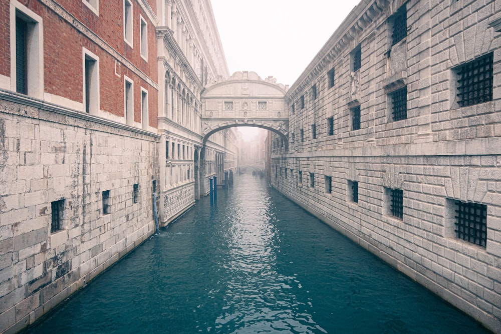 a narrow canal with a bridge in the background