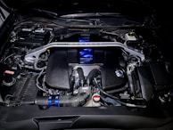 A detailed view of a motor vehicle engine component with metallic grey and dark blue highlights.