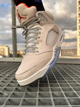 Close-up of a runner's feet on asphalt, city buildings blurred in the background, no brand visible.