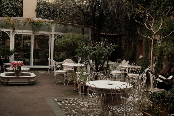 A quiet café terrace framed by ivy-covered walls, inviting solo travelers to pause and reflect