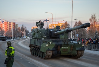 a tank driving down a street next to a crowd of people