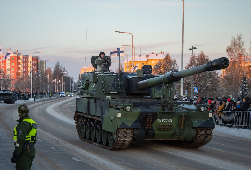 a tank driving down a street next to a crowd of people