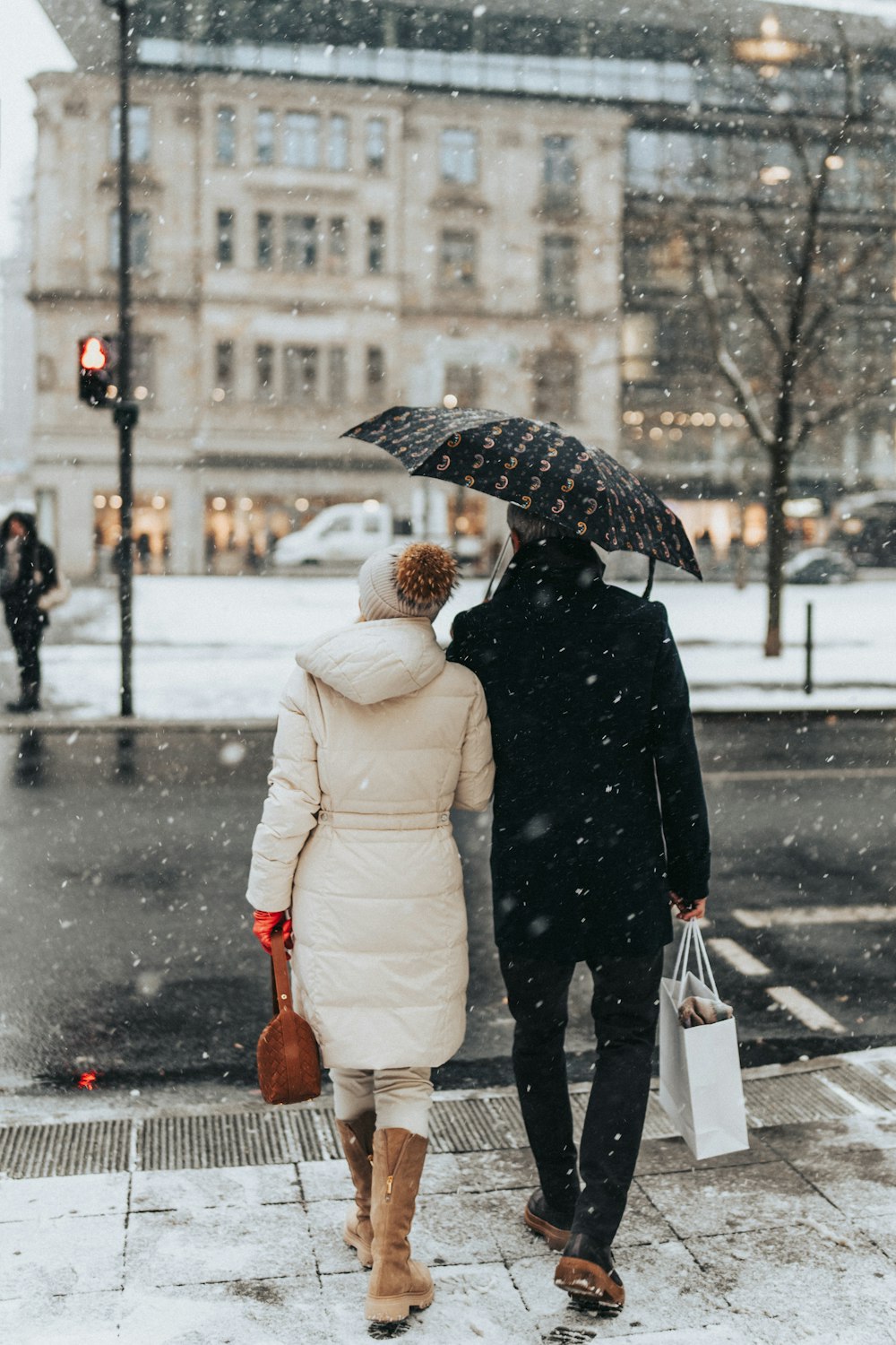 a man and woman walking down the street in the snow