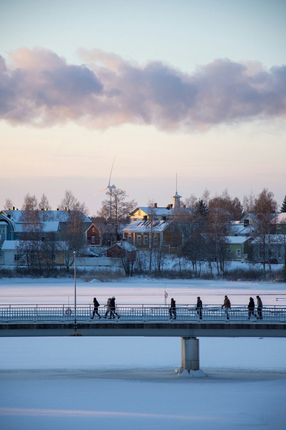 a group of people walking across a snow covered bridge