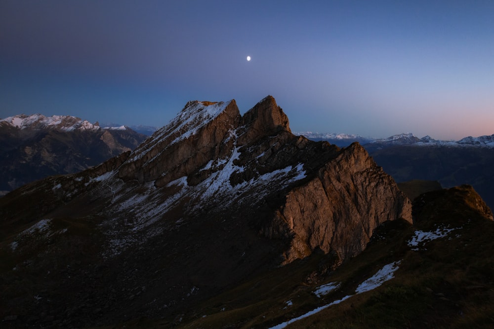 a view of a mountain with a moon in the sky