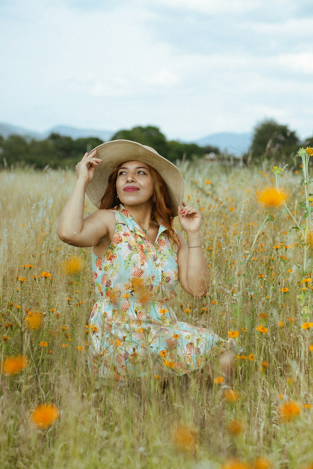 a woman sitting in a field with a hat on her head