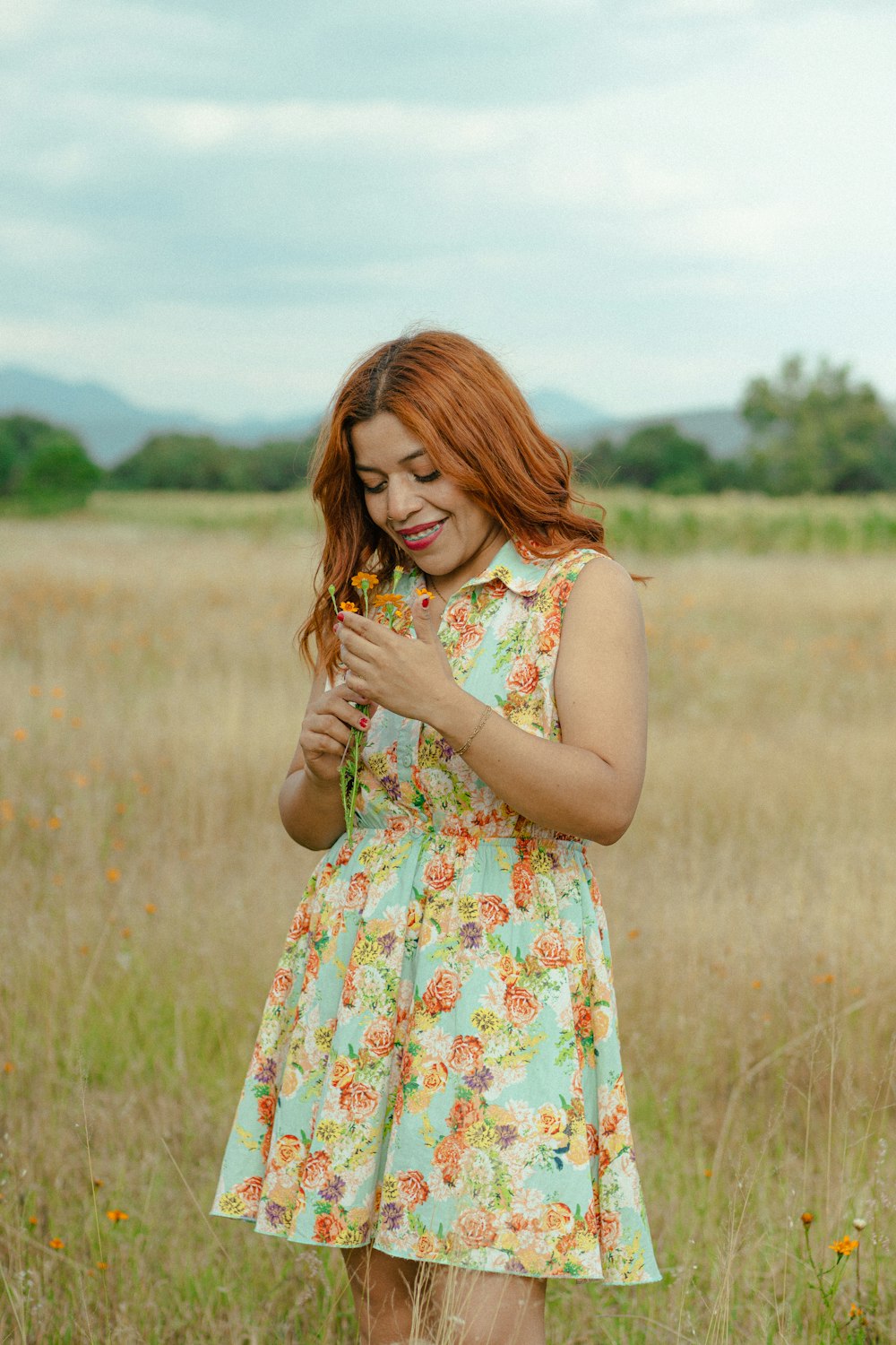 a woman standing in a field holding a flower