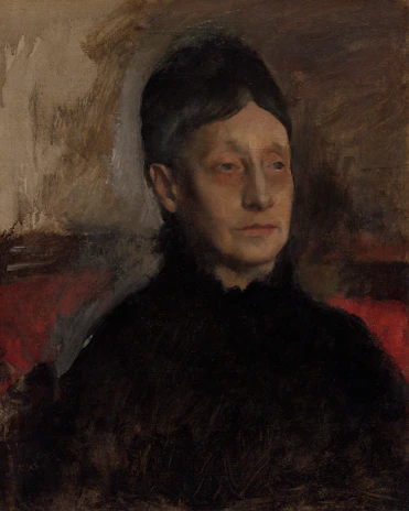 A portrait of a person with short dark hair, wearing a dark outfit, set against a blurred background with earthy tones. The facial expression appears contemplative with subtle lighting highlighting the facial features.