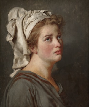 A classical portrait of a young person gazing upwards with a contemplative expression. The individual has curly hair and is wearing a draped garment, with a cloth headpiece that covers their head and partially falls onto the shoulders. The background is muted and dark, enhancing the focus on the subject.