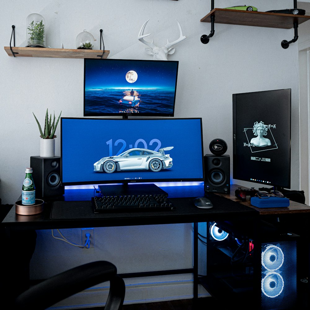 un bureau avec un moniteur, un clavier et des haut-parleurs