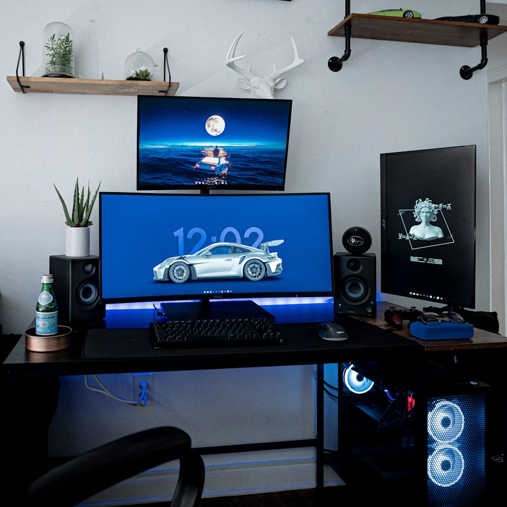 a desk with a monitor, keyboard and speakers